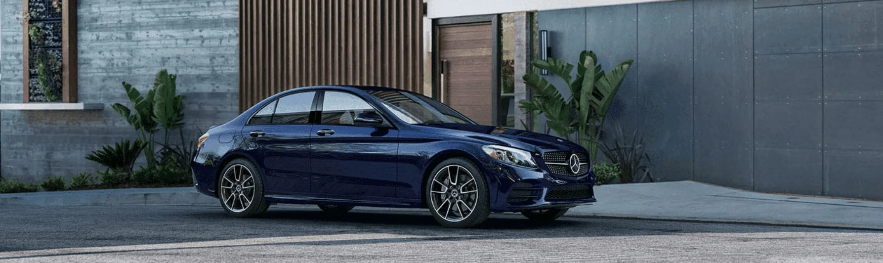 Синий седан Mercedes-Benz у современного здания